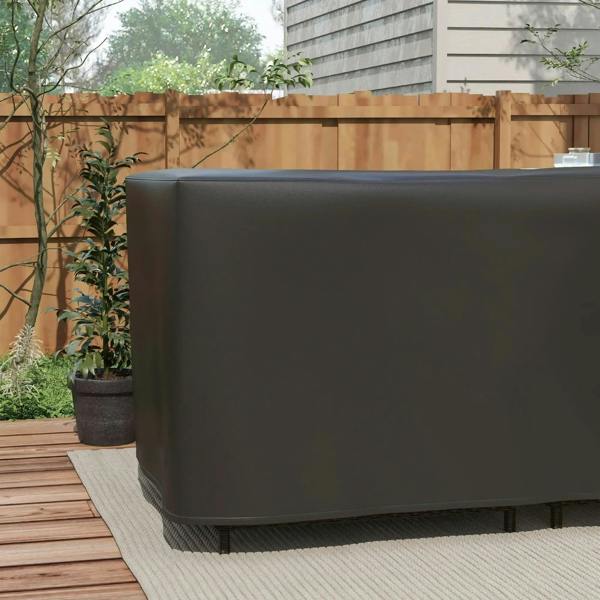 Black L-shaped protective furniture cover draped over outdoor corner sofa seat