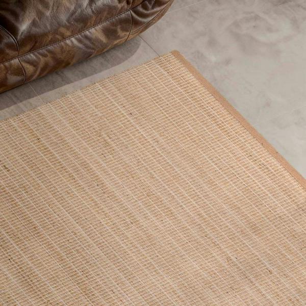 Beige woven mat on a concrete floor with a brown leather chair corner.