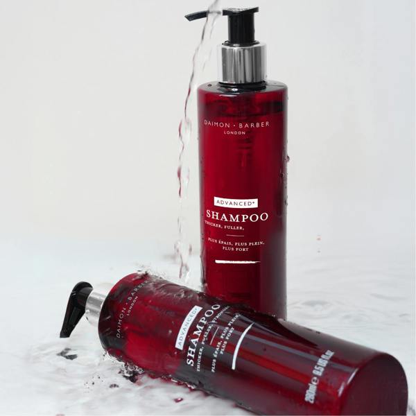 Shot of 2 Advanced+ Shampoo bottles with water running down them.