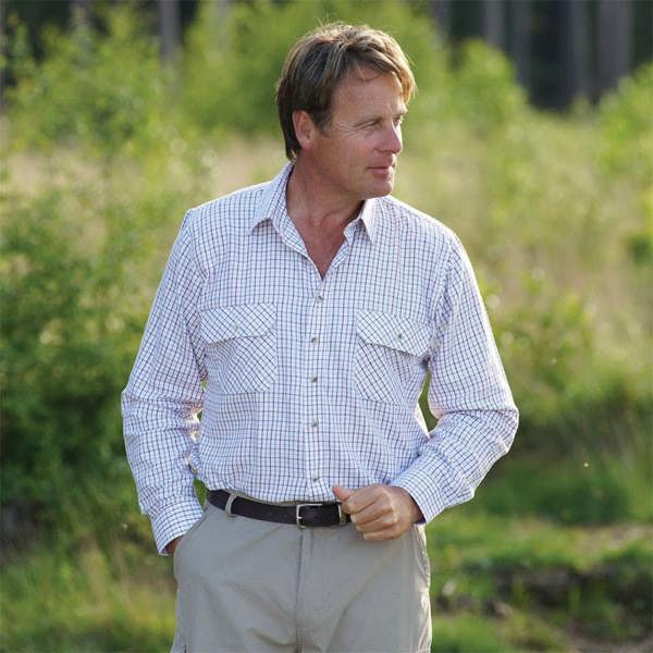 Man outdoors wearing Champion red Tattersall shirt in countryside setting, styled for rural events, shooting or seasonal workwear
