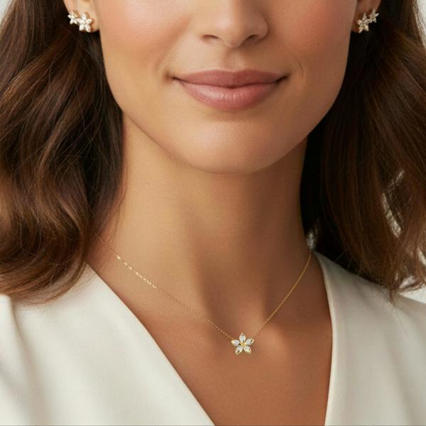 BLOOMTINE_FLOWER_NECKLACE_GOLD_VERMEIL_PERFECT_GIFT_FOR_HER. Woman wearing a gold necklace with a small flower pendant against a neutral background