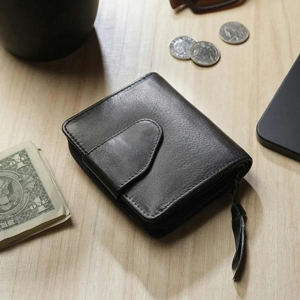 Black leather wallet on a wooden surface with coins and a phone
