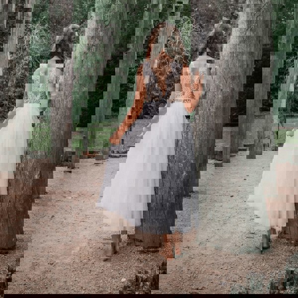 young girl stood by tree wearing pretty dress
