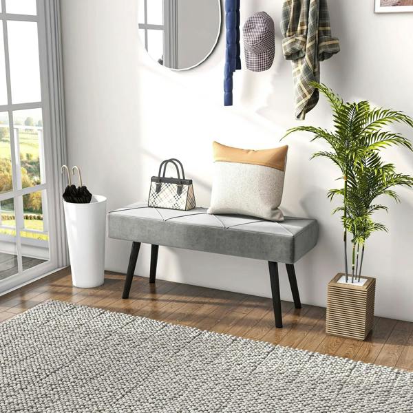 Grey upholstered bench with padded seat and dark steel legs in bright room