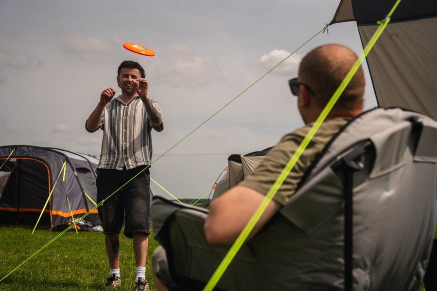 A group of males playing with a frisbee outside of the Hive 6 Berth Poled Tent by OLPRO