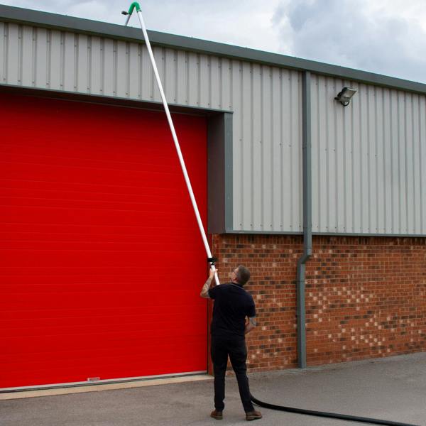 60L wet and dry vacuum with long gutter vacuum pole, user extending pole towards a high building with a red garage door in background