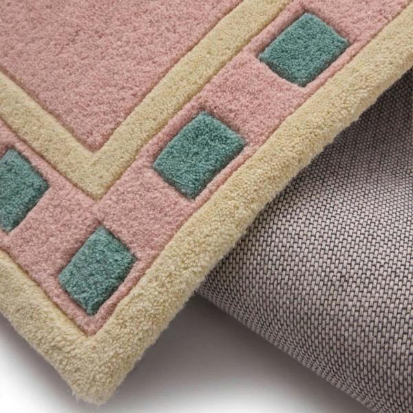 Close-up of a geometric-patterned rug with pink, green, and beige colors.