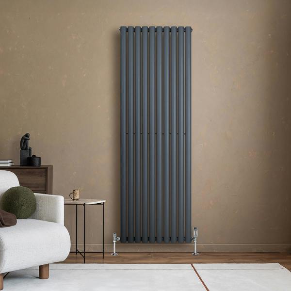 Sleek anthracite grey oval single column radiator mounted on a textured wall, complemented by stylish valves and modern decor elements