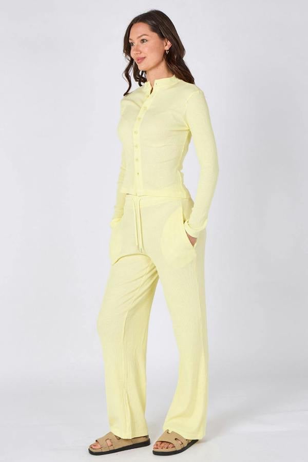 Woman wearing a light yellow jumpsuit on a white background