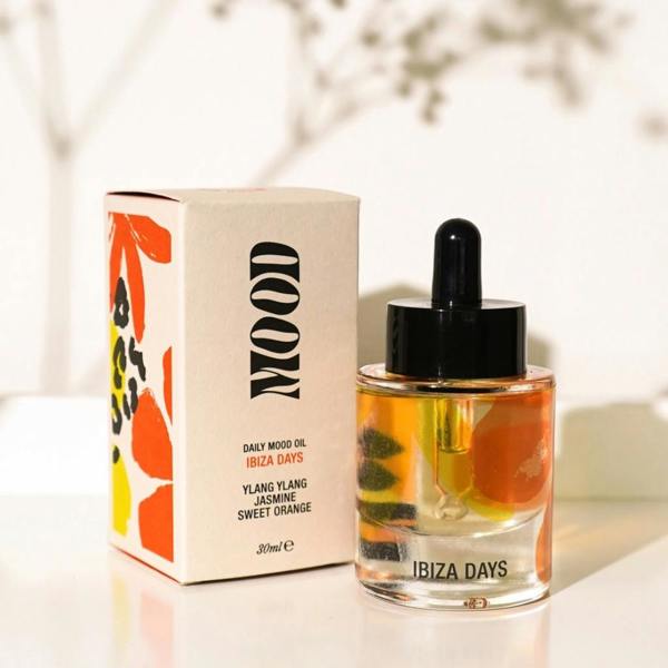 Ibiza Days Daily Aromatherapy Mood Oil bottle with glass dropper and colourful packaging next to delicate white flowers by Abode Home & Gifts