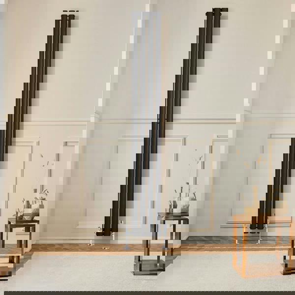 Sleek black oval single column radiator stands against a light wall, complemented by a wooden table and soft rug in a modern interior