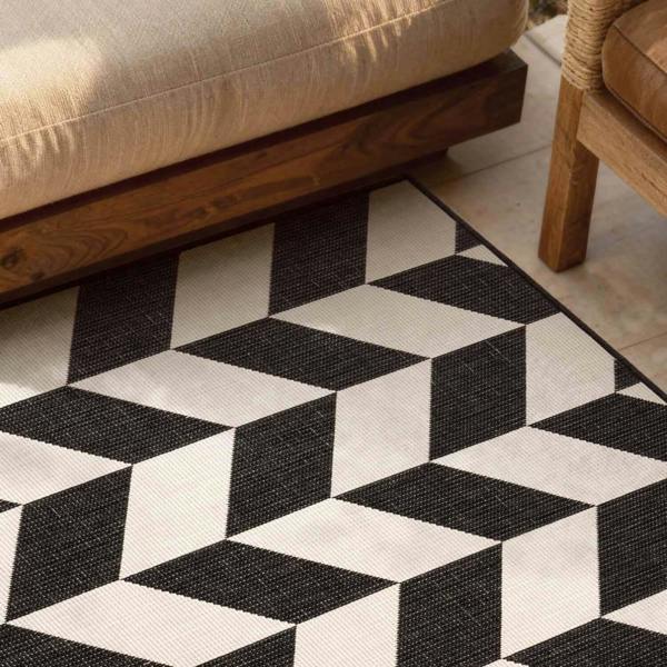 Black and white geometric patterned rug on a wooden floor with furniture.