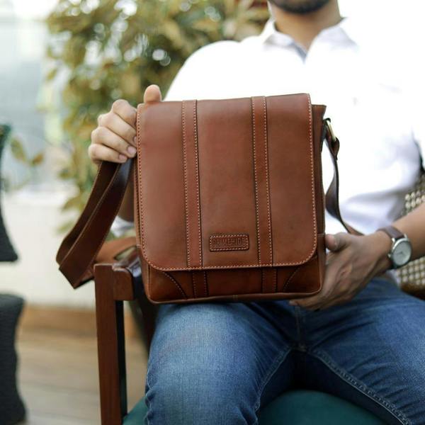 Man carrying small Brown leather messenger crossbody bag for everyday use