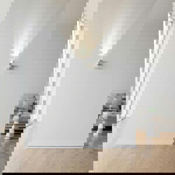 Round silver indoor wall uplight on  a white wall in a lounge