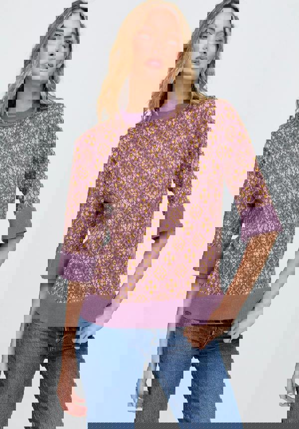 Woman wearing a patterned purple sweater and blue jeans on a white background