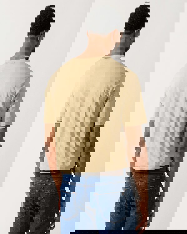 back shot of a model wearing a GANT Mens Regular Fit Short Sleeve Shield Logo T-Shirt in Oat Beige