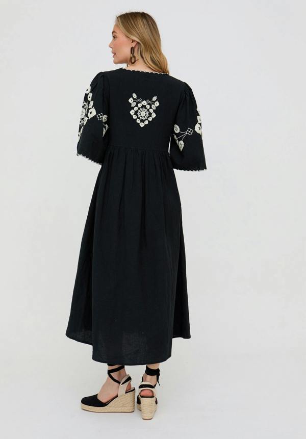 Black dress with white floral embroidery on a plain background