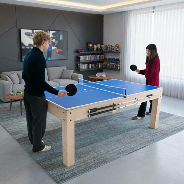 Blue tabletop 7-in-1 games table with two players enjoying table tennis, surrounded by a cozy living room setting with storage benches