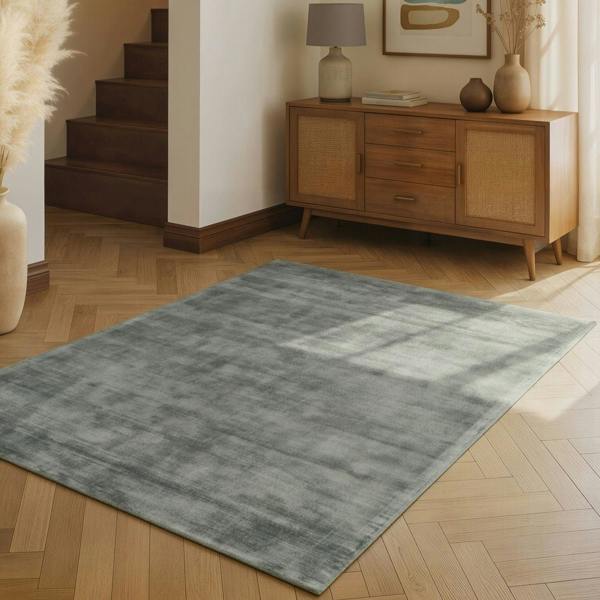 Gray rug on a wooden floor with a wooden sideboard in the background