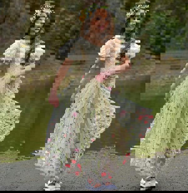 Young girl in a floral dress standing by a pond