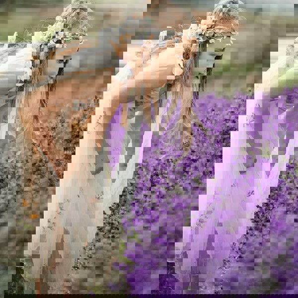 Young girl in a floral dress and crown among lavender flowers