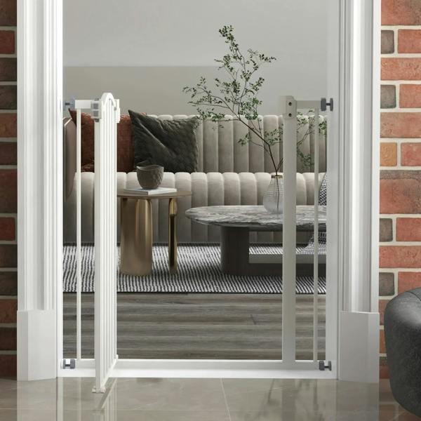 White pet gate installed in doorway with vertical bars and swing door