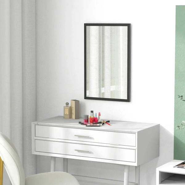 Black framed wall mirror above white vanity with countertop items