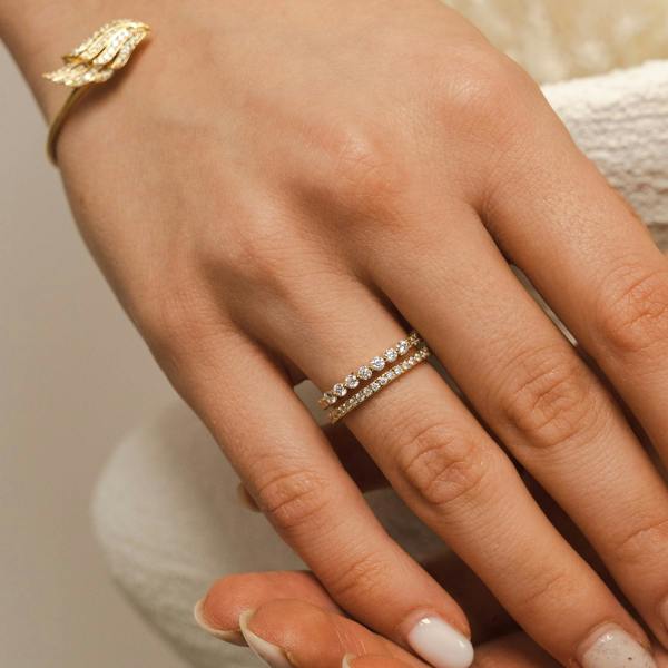 Close-up of a hand wearing two gold rings with a neutral background. The BLOOMTINE Illuminess™ Sterling Silver Combi Ring featuring a fused pavé and bezel-set design. This two-in-one moissanite stack is handcrafted in solid sterling silver with a white rhodium finish, offering the look of a curated ring stack with the comfort of a single band.