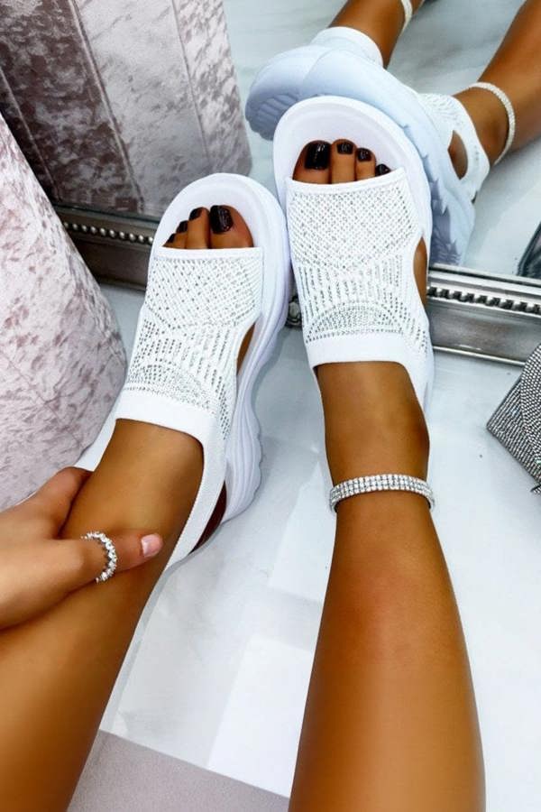 White open-toe sandals worn by a person with visible feet and legs.
