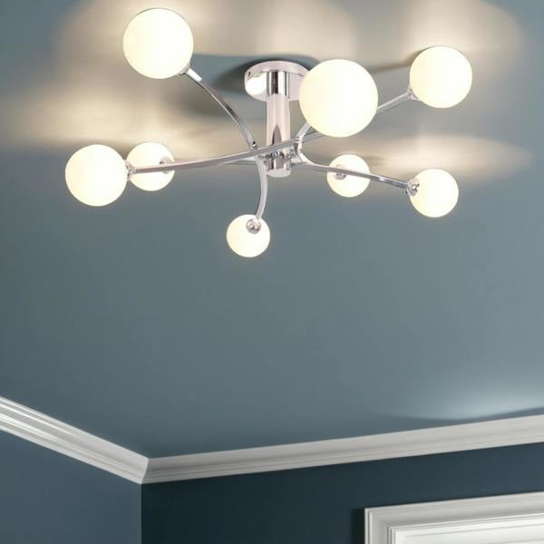 A contemporary ceiling light with a polished chrome finish, featuring curved arms and matt opal glass spheres.