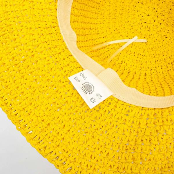 Close-up of yellow straw hat brim with light fabric inner band and tag
