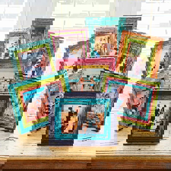 All eight colours of our Recycled Newspaper Photo Frames on a wooden table.