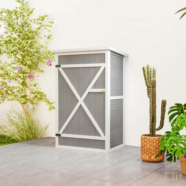 Grey wooden small storage shed with white X-brace door, standing on patio