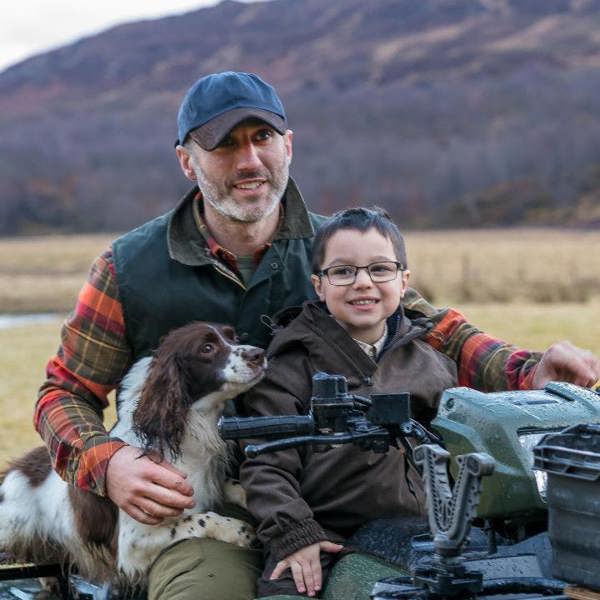 Man wearing Hoggs of Fife Wax baseball cap in Navy on back of quad with child