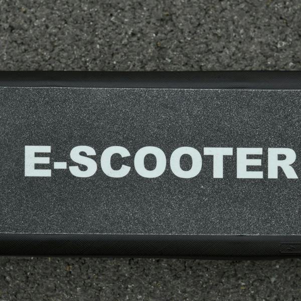 Textured black electric scooter deck with anti-slip surface and E-SCOOTER lettering