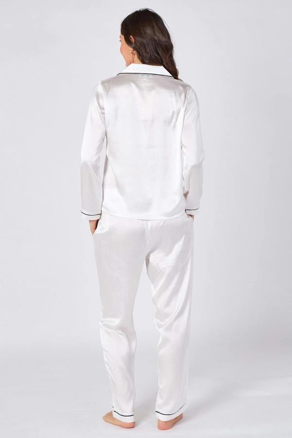 Woman wearing a white satin pajama set on a white background
