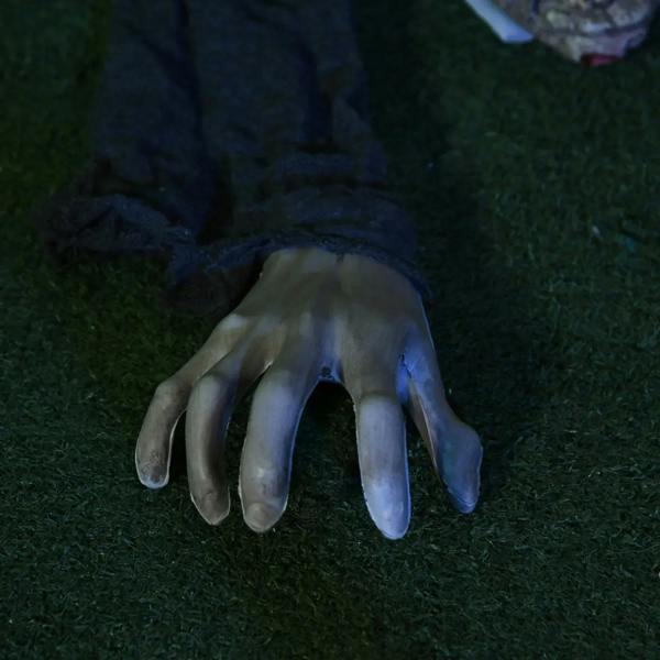 Zombie decoration hands with long fingers and glowing red eyes, grey fabric