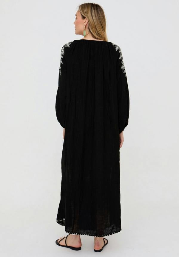 Woman wearing a black dress with floral embellishments on a white background
