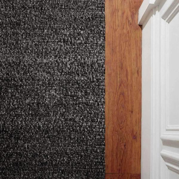 Gray carpeted floor transitioning to wooden flooring with a white baseboard.