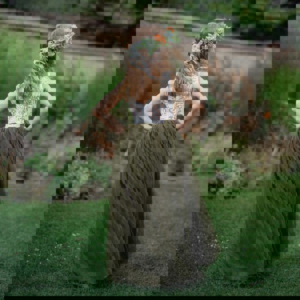 Girl in a green dress with floral headband standing in a garden