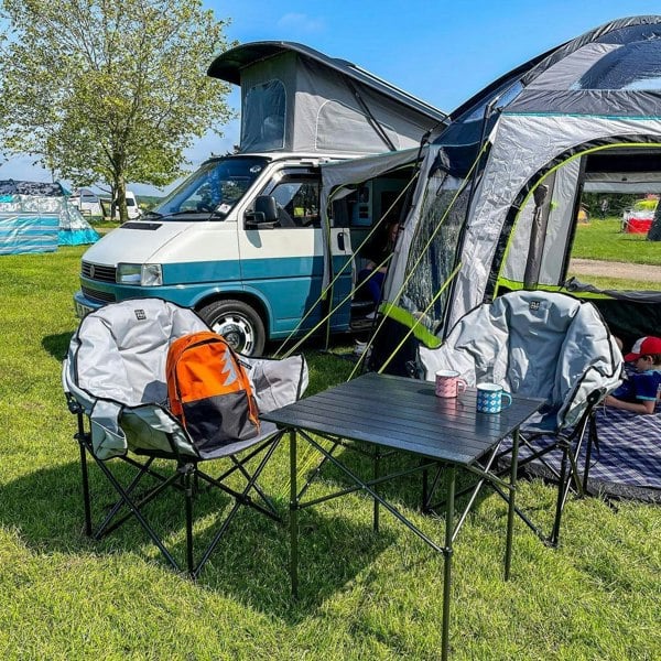 An image of a family using Folding Camp Table from OLPRO on a campsite whilst using a campervan awning.