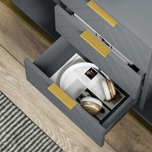 Grey sideboard drawer open with gold handle, holding magazines and small items