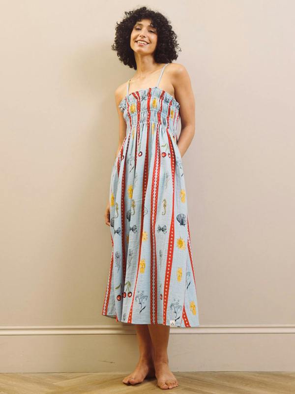 Woman wearing a colorful patterned night dress against a beige wall.