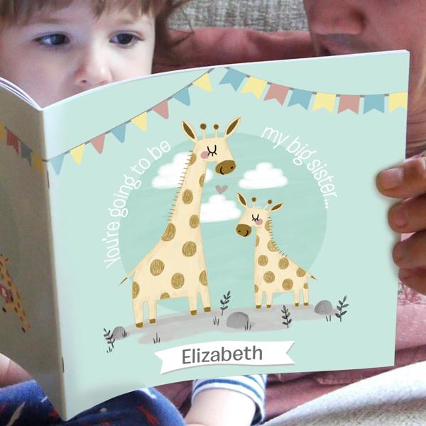 A child reading a light blue personalised big sister book featuring a mother and baby giraffe illustration with the name Elizabeth.