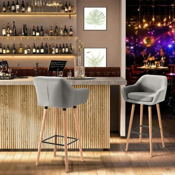 Set of 2 grey upholstered bar chairs with black footrests and light wood legs