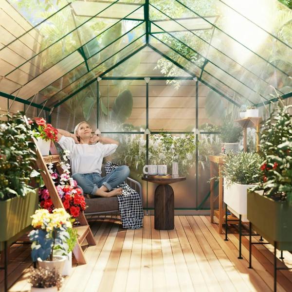 Sunny interior scene inside a clear polycarbonate greenhouse with seating, tables, and potted plants.
