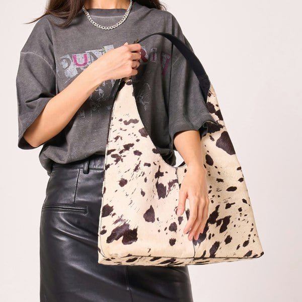 Image shows the cow hide bag from another angle, focusing on the natural variation of the print.