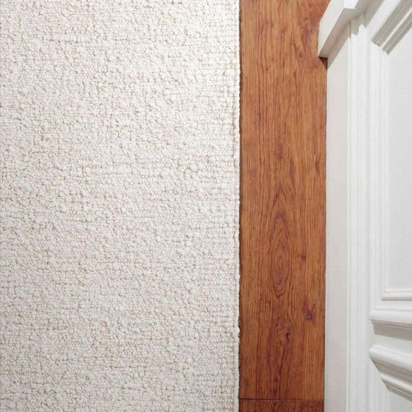 Close-up of a textured white wall with a wooden panel and architectural details.