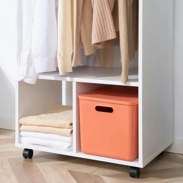 Lower shelf of white mobile wardrobe with orange storage box and caster wheels