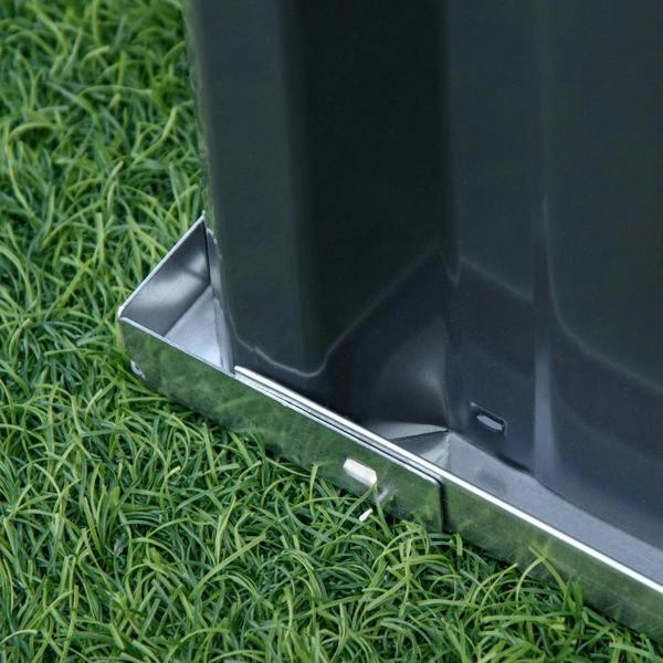 Corner close-up of a dark gray metal raised garden bed on grass with open base